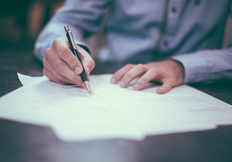 A person at a desk writing notes and organising paperwork.