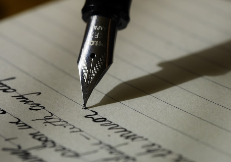 A fountain pen writing longhand on paper, mid-sentence.