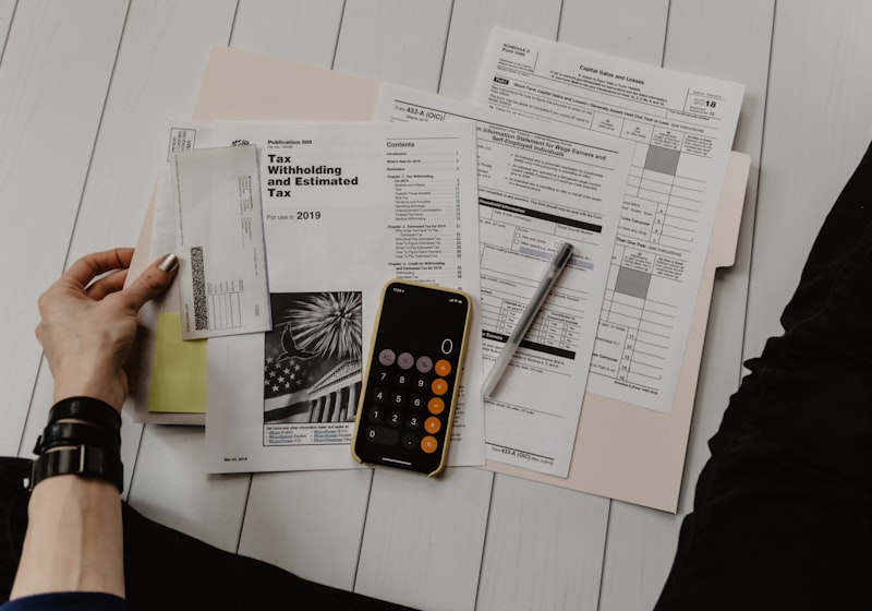 Printed reports and figures spread across a desk beside a calculator.