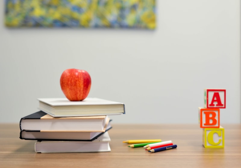 A stack of books with lettered blocks and an apple, evoking learning.