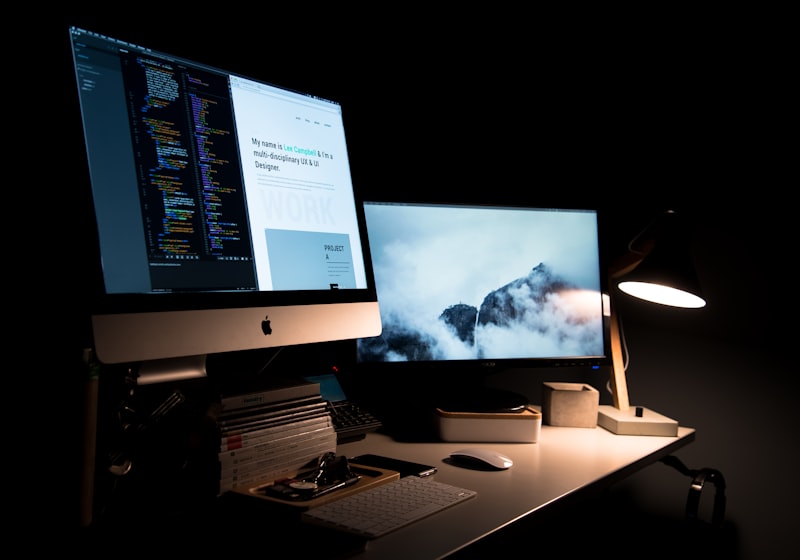 A developer's multi-monitor workstation showing code alongside a website dashboard.