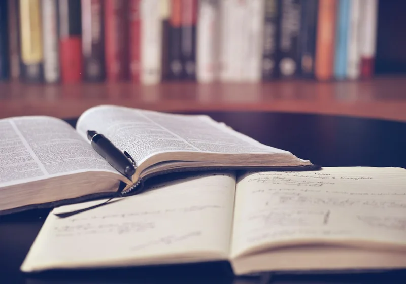 An open book with notes over library shelves — academic and professional research.